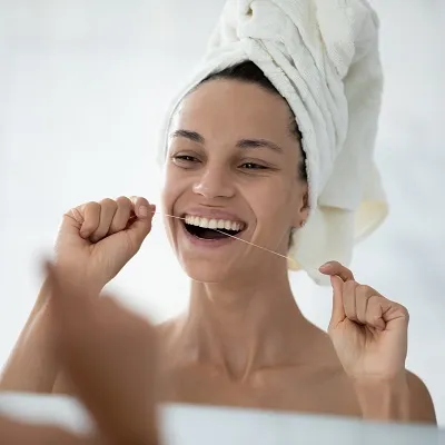 Smiling woman looking in the mirror and flossing.