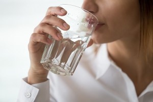 A woman in a white shirt drinking a glass of water
