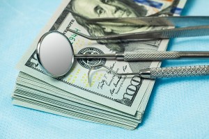 A stack of money with dental tools on top