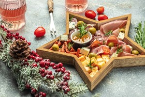 A holiday themed charcuterie board in a star platter next to a holiday garland.