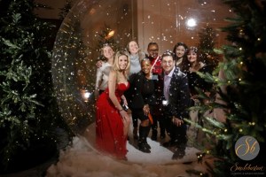 The smileboston team smiling in a snowglobe with trees in the background