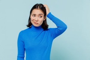 a woman in a blue sweater with short dark hair with a confused expression