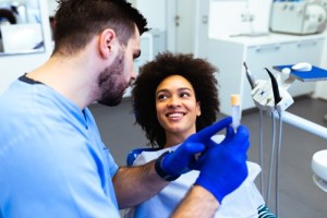 Woman receiving dental treatment from a person wearing scurbs and blue gloves