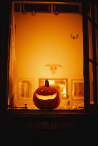 a pumpkin carved with a smiling face set in a window with an orange room in the background
