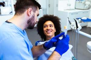 Woman receiving dental treatment from a person wearing scurbs and blue gloves
